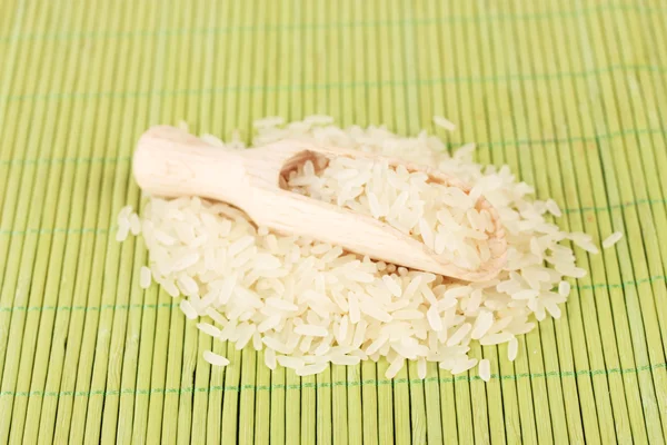 Ris i trä scoop på bambu matta — Stockfoto