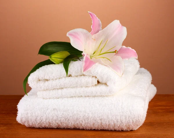 Stapel handdoeken met roze lelie op een bruine achtergrond — Stockfoto