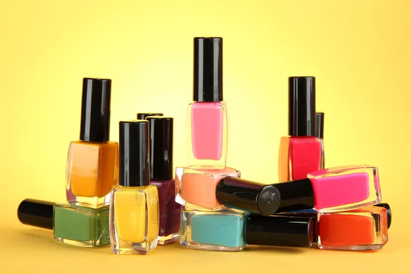 Grupo de esmaltes de uñas brillantes, sobre fondo amarillo — Foto de Stock