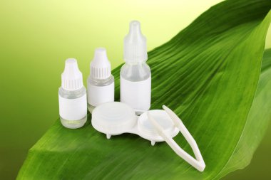 Göz damlaları ve yaprak yeşil zemin üzerine lensler