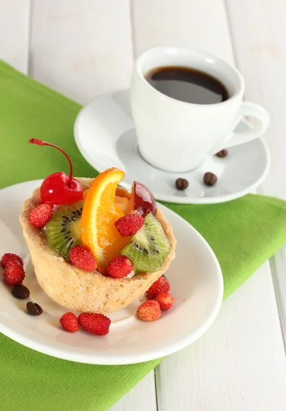 Słodkie ciasto z owocami na płytkę i filiżankę kawy na drewnianym stole — Zdjęcie stockowe