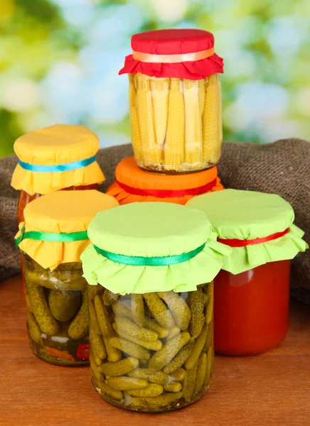 Jars with canned vegetables on green background close-up — Stock Photo, Image