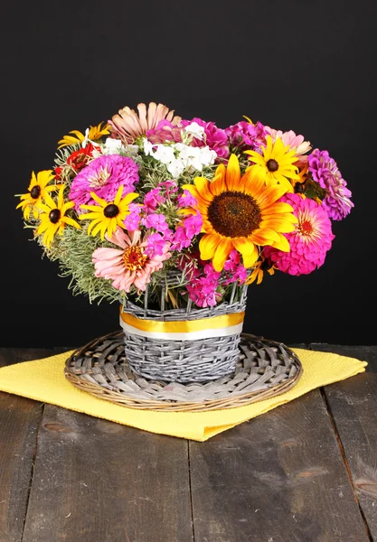 Bellissimo bouquet di fiori luminosi su tavolo di legno su sfondo nero — Foto Stock