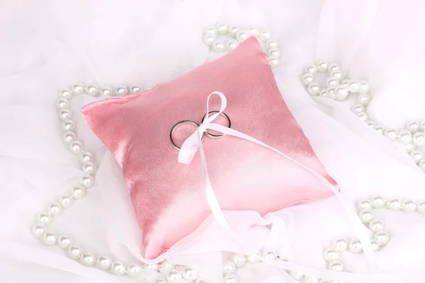 Wedding rings on satin pillow on white cloth background — Stock Photo, Image