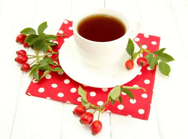 Tazza di tè con rose dell'anca, sul tavolo di legno — Foto Stock