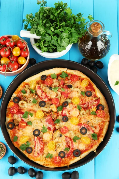 Composición colorida de deliciosa pizza, verduras y especias en madera azul —  Fotos de Stock