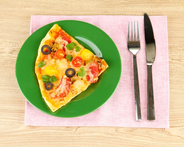 Assiette avec une tranche de délicieuse pizza sur fond en bois — Photo