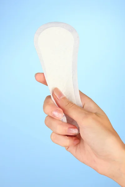 Woman's hand holding a daily sanitary pad on blue background close-up — Stock Photo, Image