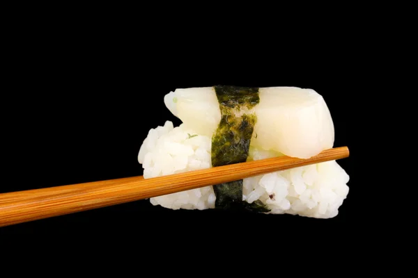 Tenendo sushi con bacchette isolate su nero — Foto Stock