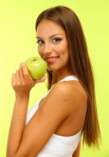 Beautiful young woman with green apple, on green background — Stock Photo, Image