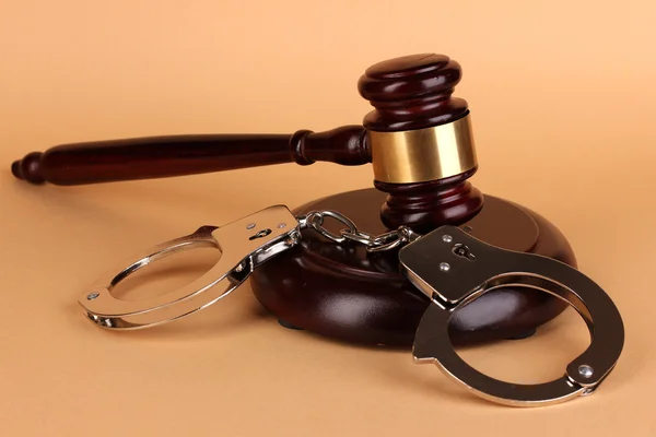 Gavel and handcuffs on beige background — Stock Photo, Image