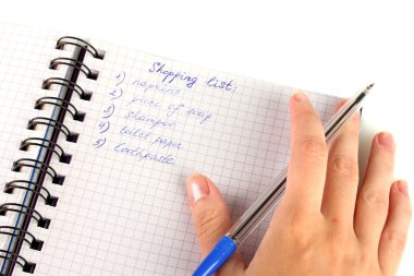 Kadının elinde alışveriş listesi olan bir defter var.
