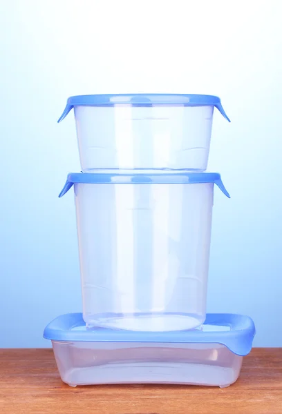 Plastbehållare för mat på träbord på blå bakgrund — Stockfoto