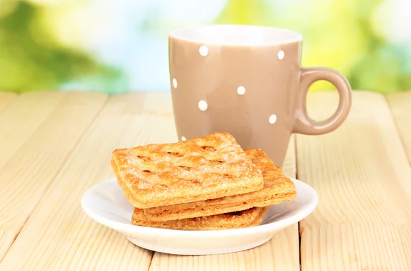 Tasse de thé et biscuits sur table en bois sur fond lumineux — Photo