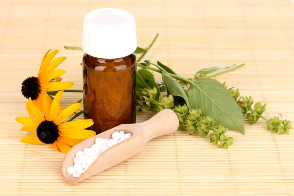 Medicin flaska med tabletter och blommor på bambu matta — Stockfoto