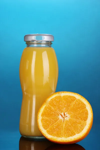 Вкусный апельсиновый сок в бутылке и апельсин рядом с ним на цветном нарциссе — стоковое фото