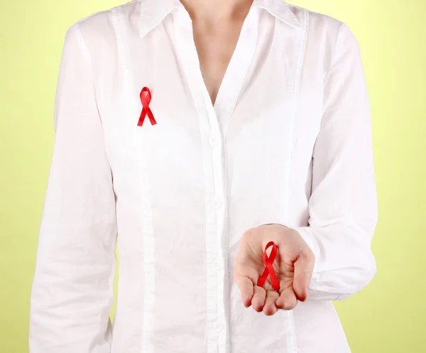 Woman with red ribbon in hands on green background — Stock Photo, Image