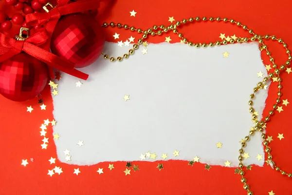 Belas bolas de Natal brilhantes e cartão postal vazio no fundo vermelho — Fotografia de Stock
