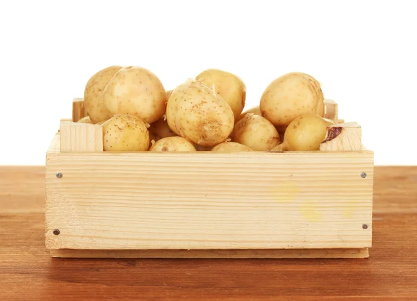 Junge Kartoffeln in einer Holzkiste auf einem Tisch auf weißem Hintergrund Nahaufnahme — Stockfoto