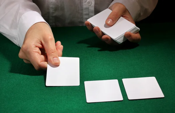 Cards in hands on green table — Stock Photo, Image