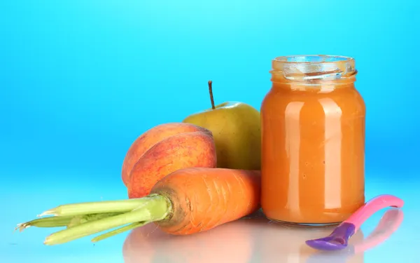 Jar with fruit and vegetables baby food and spoon on colorful background — Stock Photo, Image