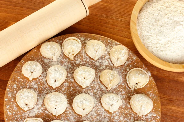 Dumplings crudos sobre tabla de cortar sobre fondo de madera close-up — Foto de Stock