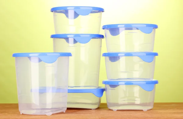 Recipientes de plástico para alimentos em mesa de madeira em fundo verde — Fotografia de Stock