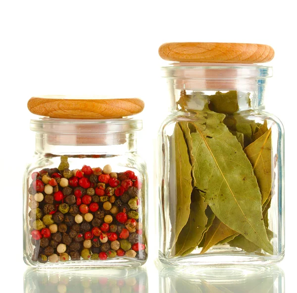 Folhas de louro e especiarias de pimenta em frascos de vidro isolados em branco — Fotografia de Stock