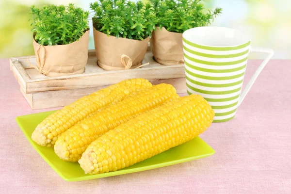 Boiled corn on the pink table cloths on the background of nature — Stock Photo, Image