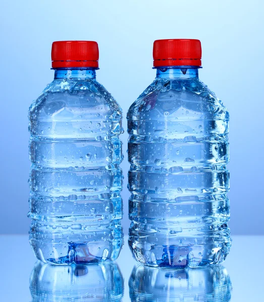 Bottiglie di plastica di acqua su sfondo blu — Foto Stock