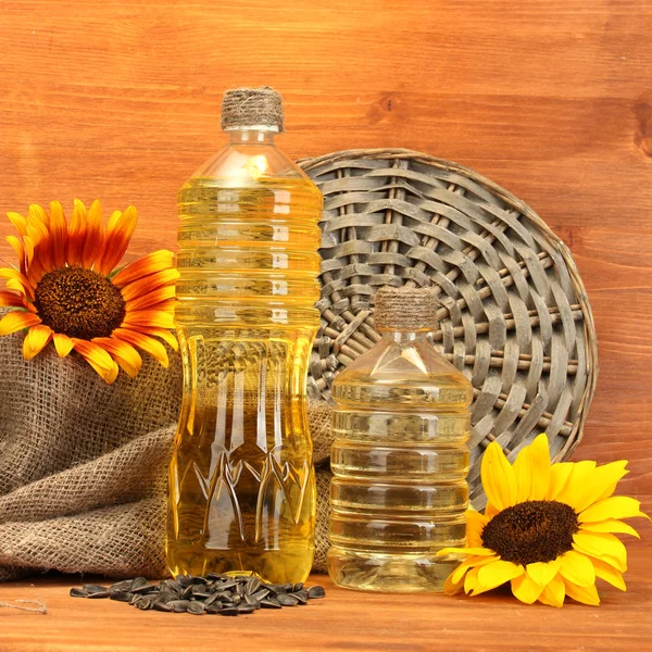 Aceite en botellas, girasoles y semillas, sobre fondo de madera —  Fotos de Stock