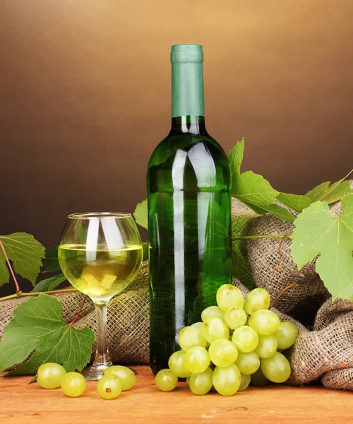 Botella de gran vino con copa sobre mesa de madera sobre fondo marrón — Foto de Stock