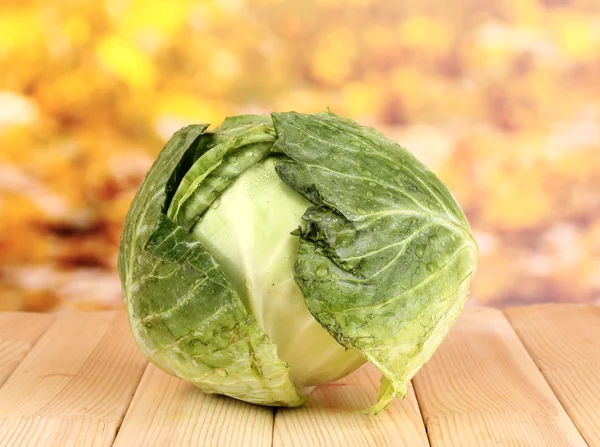 Fresh cabbage on wooden table on colorful background — Stock Photo, Image