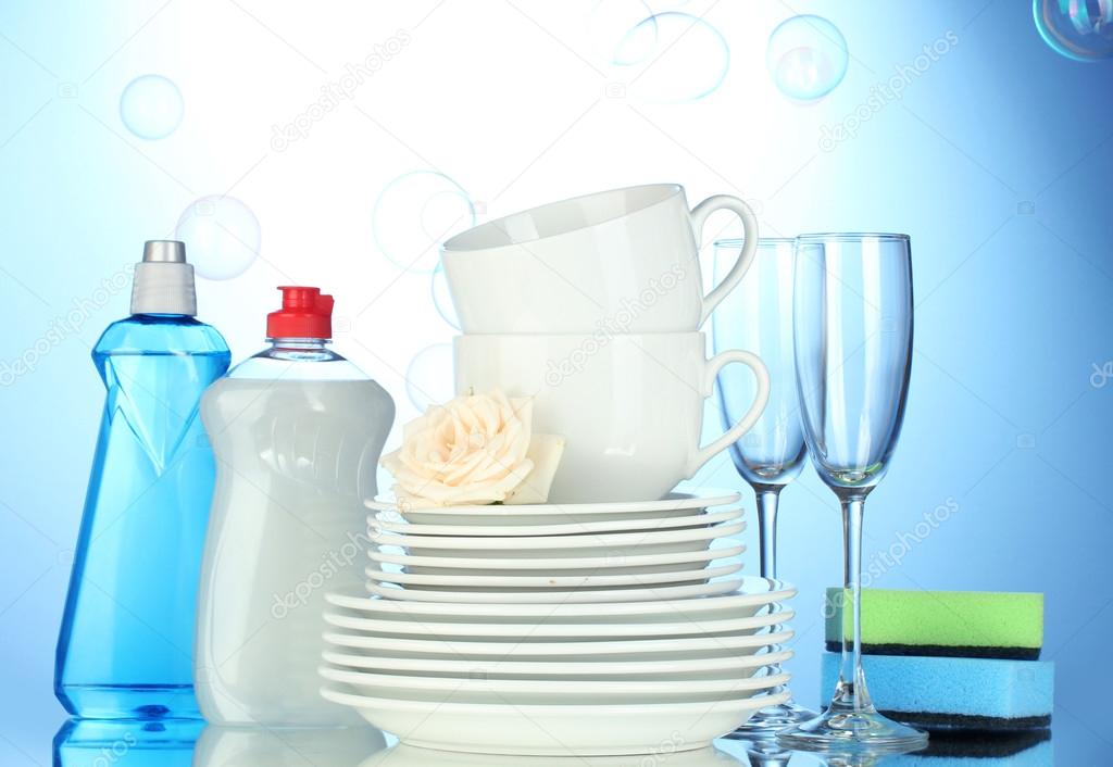 empty clean plates, glasses and cups with dishwashing liquid and sponges on