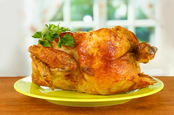 Жареная целая курица на зеленой тарелке на деревянном фоне крупным планом — стоковое фото