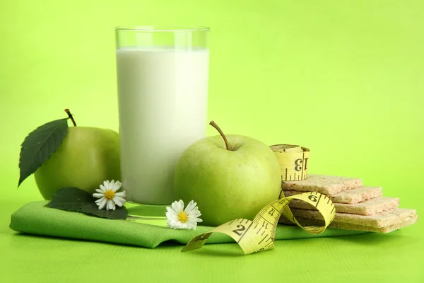Glas kefir, appels, crispbreads en meetlint, op groene achtergrond — Stockfoto