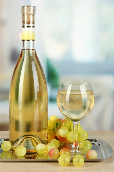 Weißwein im Glas mit Flasche auf Salver auf Zimmerhintergrund — Stockfoto