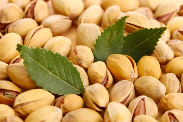 Sabrosas nueces de pistacho con hojas, de cerca —  Fotos de Stock