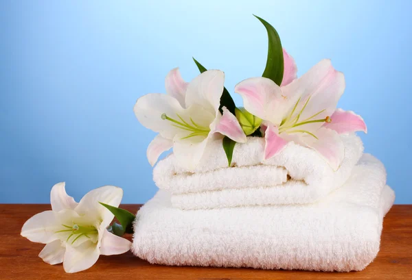 Stapel handdoeken met roze lelie op blauwe achtergrond — Stockfoto