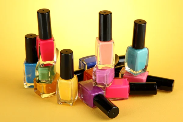 Group of bright nail polishes, on yellow background — Stock Photo, Image