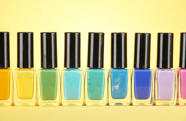 Group of bright nail polishes, on yellow background — Stock Photo, Image