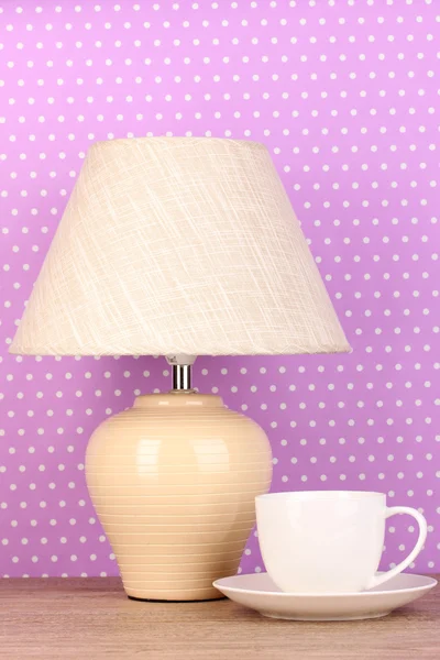 Tischlampe und Tasse auf lila Tupfen Hintergrund — Stockfoto