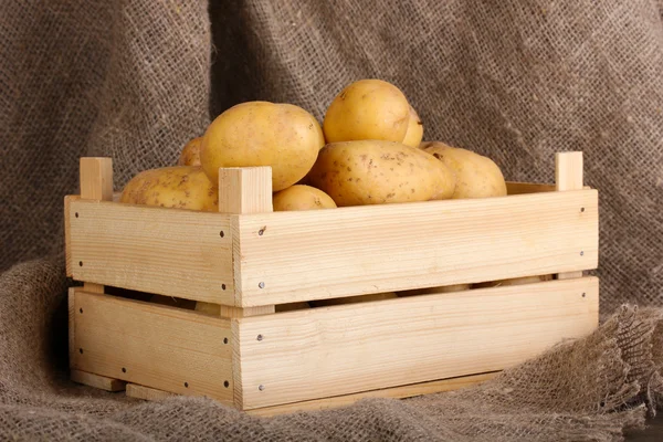 Ripe potatoes in wooden box on sacking — Stock Photo, Image