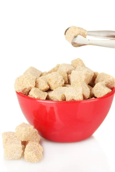 Cubes de sucre de canne brun dans un bol avec des pinces à sucre sur fond blanc — Photo