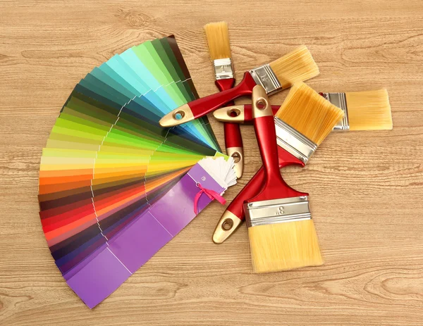 Paint brushes and bright palette of colors on wooden background — Stock Photo, Image