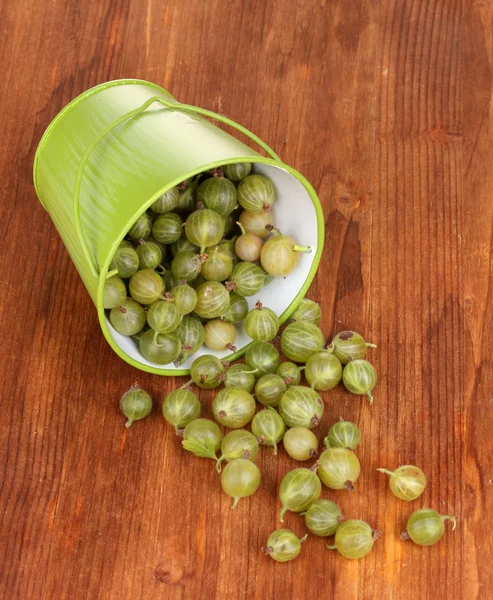 Green gooseberry in metal bucket on wooden background — Stock Photo, Image