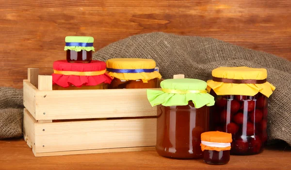 Jars with canned fruit on wooden background — Stock Photo, Image