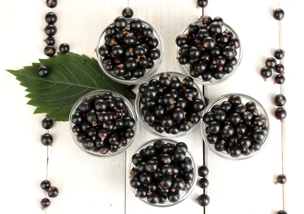 Fresh black currant in transparent bowls on white wooden background close-u — Stock Photo, Image