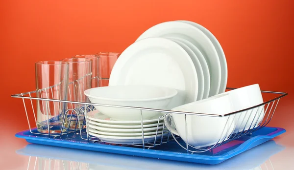 Clean dishes on stand on red background — Stock Photo, Image