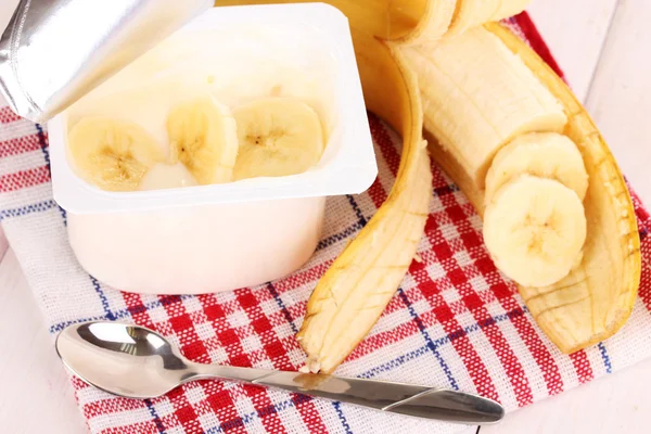 Yogurt with a banana on wooden background — Stock Photo, Image